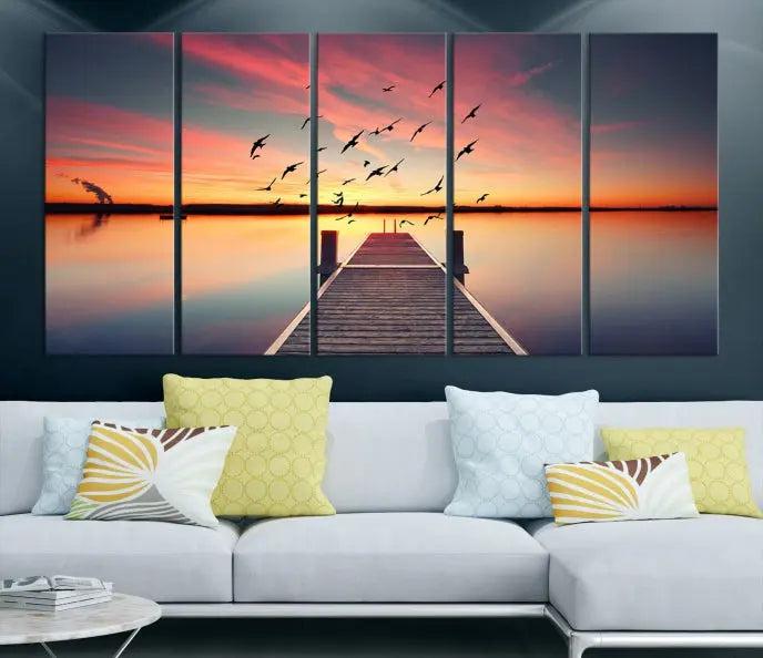 The Wood Bridge and Sunset Wall Art Canvas Print showcases a tranquil sunset scene featuring a wooden dock, soaring birds, and a vibrant sky. It comes ready to hang.