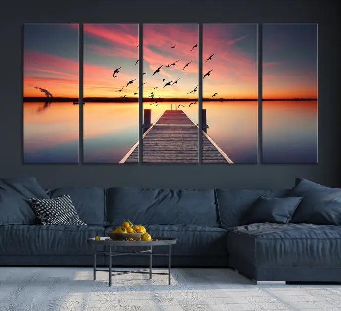 The Wood Bridge and Sunset Wall Art Canvas Print showcases a tranquil sunset scene featuring a wooden dock, soaring birds, and a vibrant sky. It comes ready to hang.