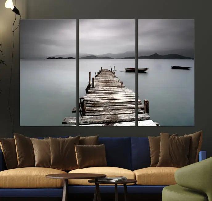 The Wood Pier Wall Art Canvas Print, a triptych featuring a wooden pier stretching into a tranquil, misty lake, is elegantly displayed in the room. This gallery-wrapped artwork is crafted from museum-quality polycotton and includes a UV-protective coating to ensure durability and vibrant colors for years to come.