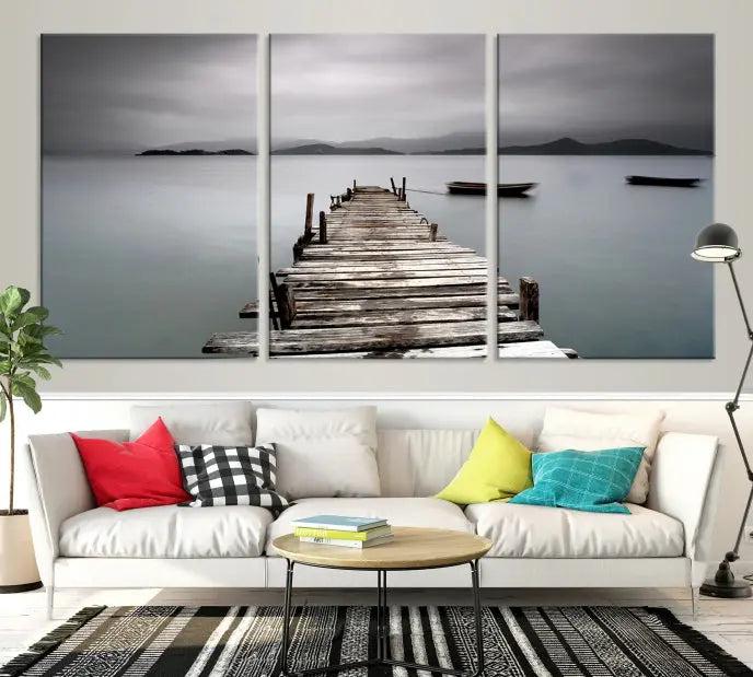 The Wood Pier Wall Art Canvas Print, a triptych featuring a wooden pier stretching into a tranquil, misty lake, is elegantly displayed in the room. This gallery-wrapped artwork is crafted from museum-quality polycotton and includes a UV-protective coating to ensure durability and vibrant colors for years to come.