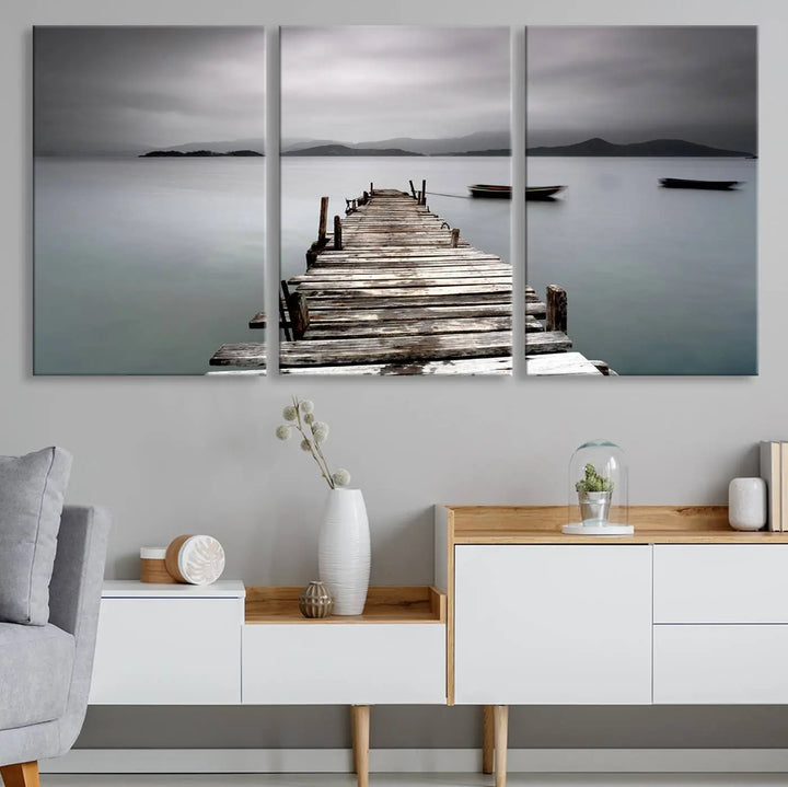 A serene triptych featuring a wooden pier stretching into misty waters brings the Wooden Pier Canvas Wall Art Beach Canvas Artwork Print to life.