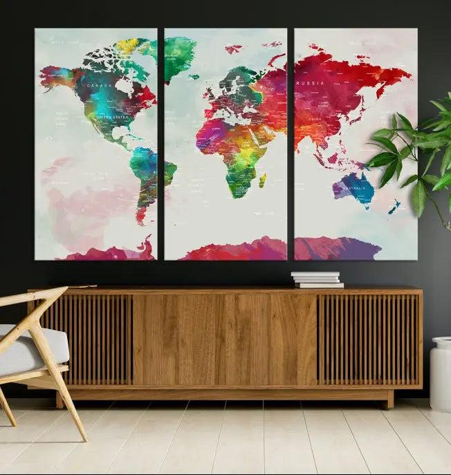 The World Map Wall Art, featuring a triptych design with vibrant continents, is printed on museum-quality canvases and displayed against a dark wall.