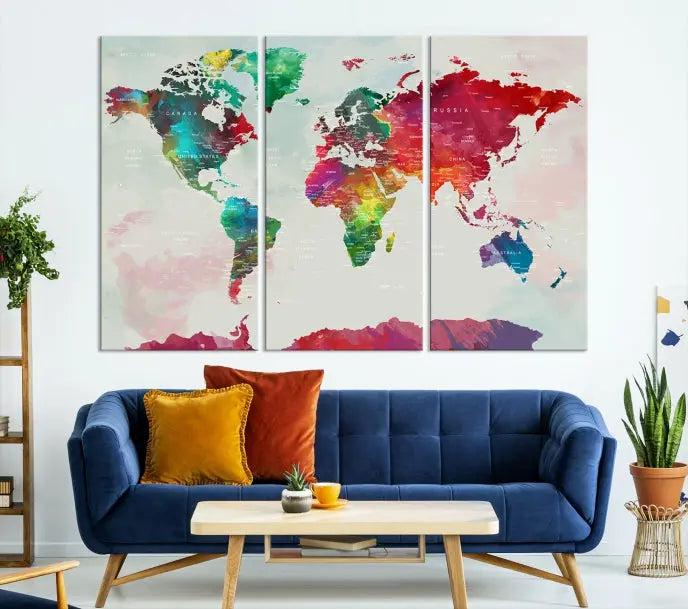 The World Map Wall Art, featuring a triptych design with vibrant continents, is printed on museum-quality canvases and displayed against a dark wall.