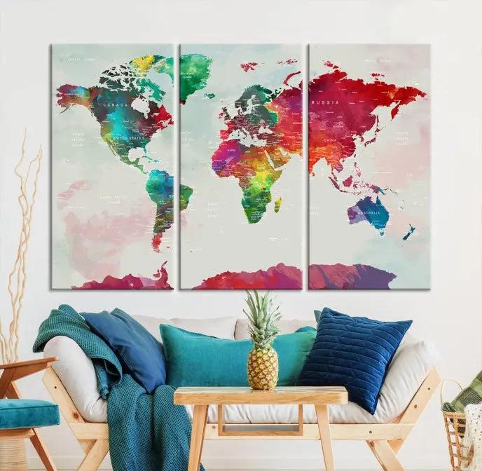 The World Map Wall Art, featuring a triptych design with vibrant continents, is printed on museum-quality canvases and displayed against a dark wall.