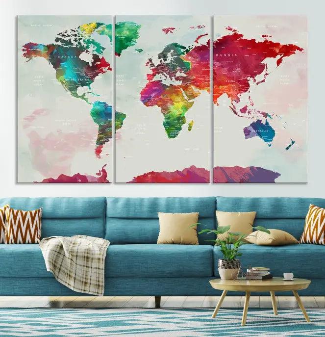 The World Map Wall Art, featuring a triptych design with vibrant continents, is printed on museum-quality canvases and displayed against a dark wall.