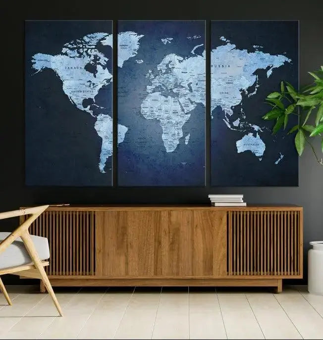 A modern living room featuring a World Map Wall Art Canvas Print in triptych format.