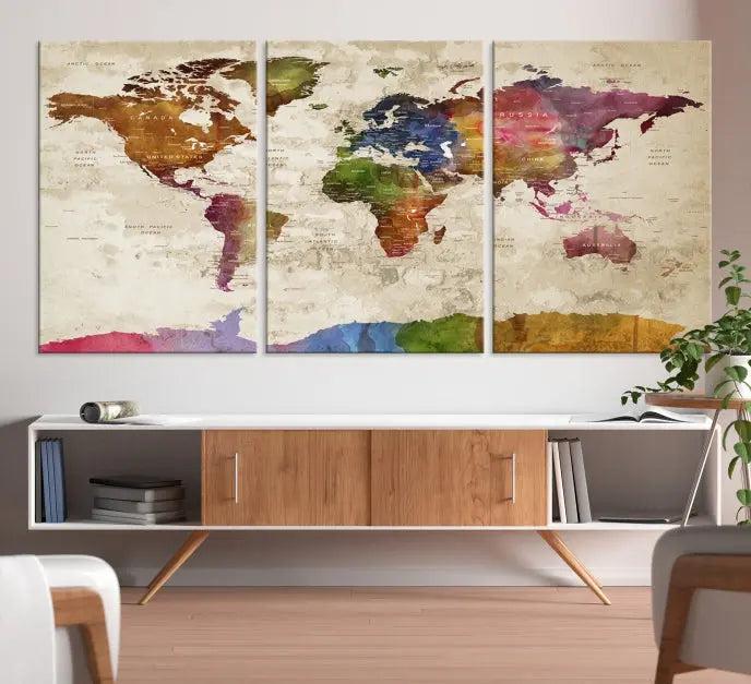 The World Map Wall Art Canvas Print, featuring a vibrant triptych design on museum-quality canvases, decorates the wall. The gallery-wrapped artwork is treated with a UV-protective coating to ensure its colors remain vivid over time.