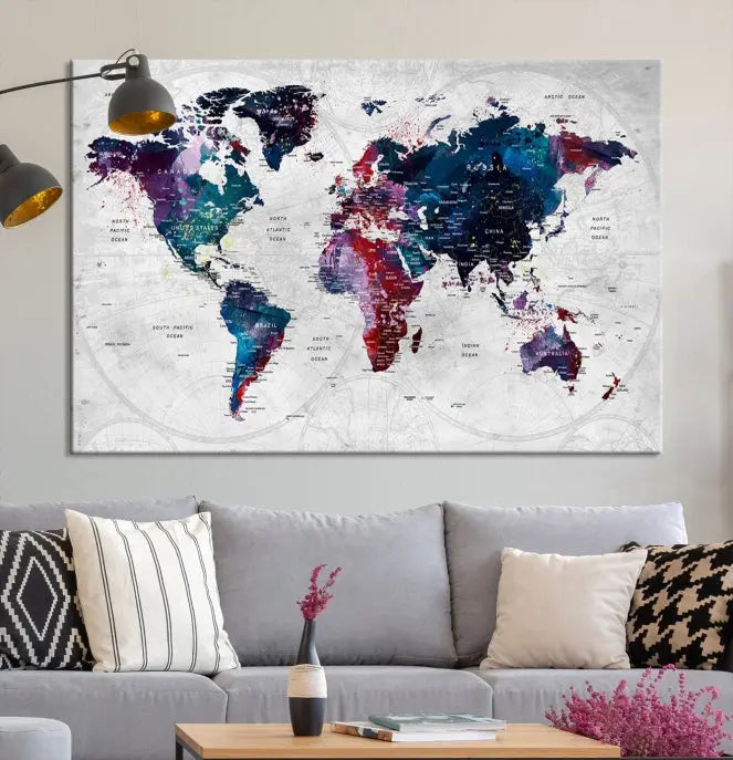 The "World Map Wall Art Watercolor Wall Art Canvas Print," a triptych featuring a vibrant world map, is gallery wrapped on museum-quality canvas and enhances the dark wall.