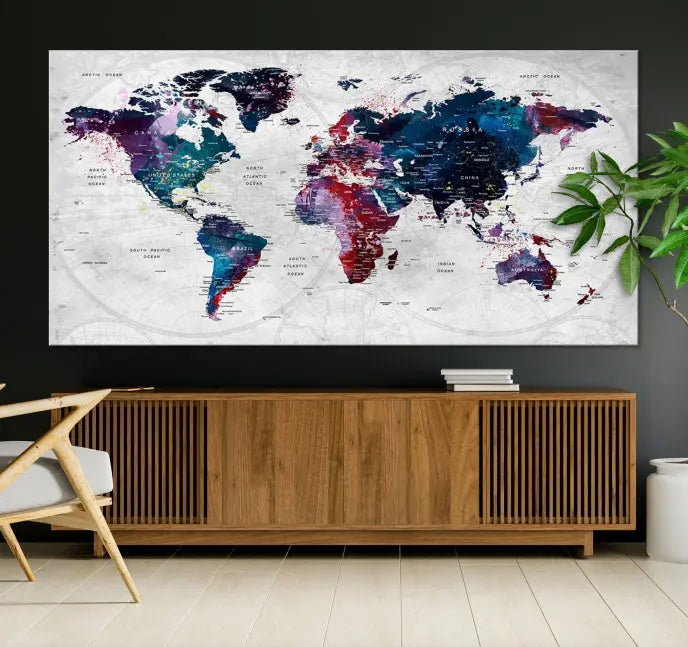 The "World Map Wall Art Watercolor Wall Art Canvas Print," a triptych featuring a vibrant world map, is gallery wrapped on museum-quality canvas and enhances the dark wall.