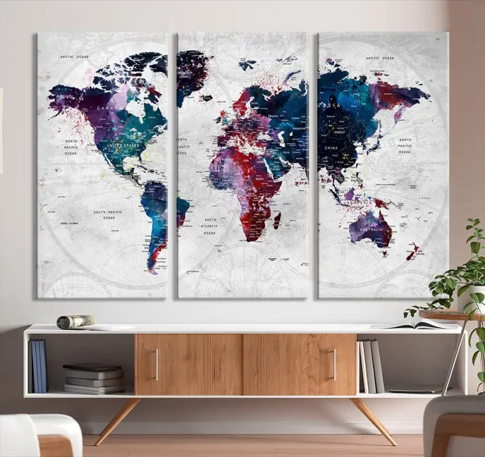 The "World Map Wall Art Watercolor Wall Art Canvas Print," a triptych featuring a vibrant world map, is gallery wrapped on museum-quality canvas and enhances the dark wall.