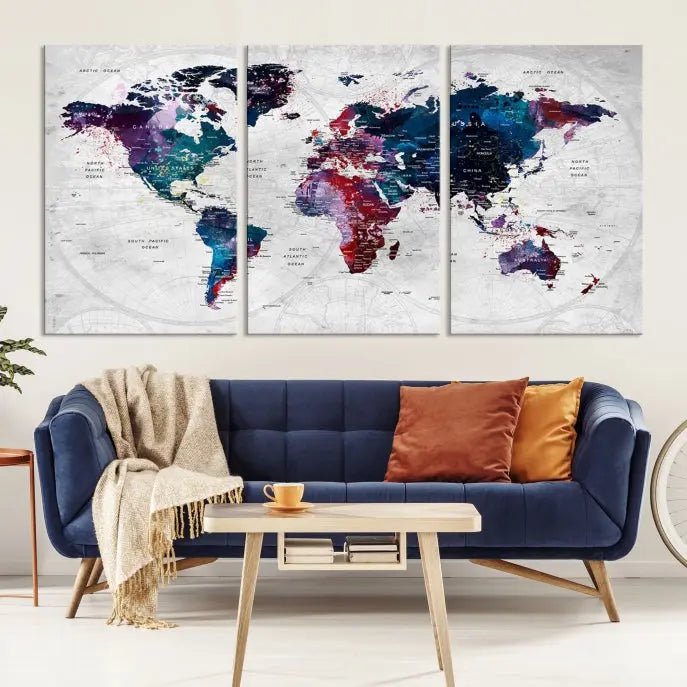 The "World Map Wall Art Watercolor Wall Art Canvas Print," a triptych featuring a vibrant world map, is gallery wrapped on museum-quality canvas and enhances the dark wall.