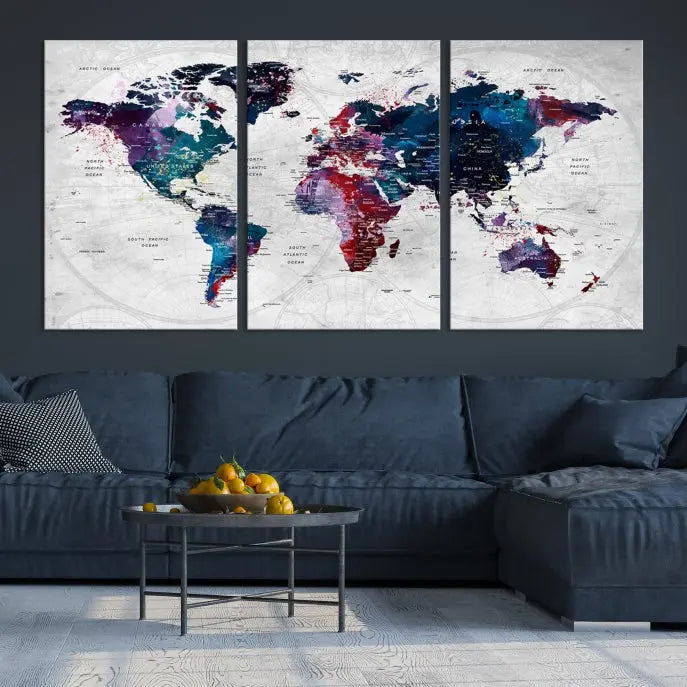 The "World Map Wall Art Watercolor Wall Art Canvas Print," a triptych featuring a vibrant world map, is gallery wrapped on museum-quality canvas and enhances the dark wall.