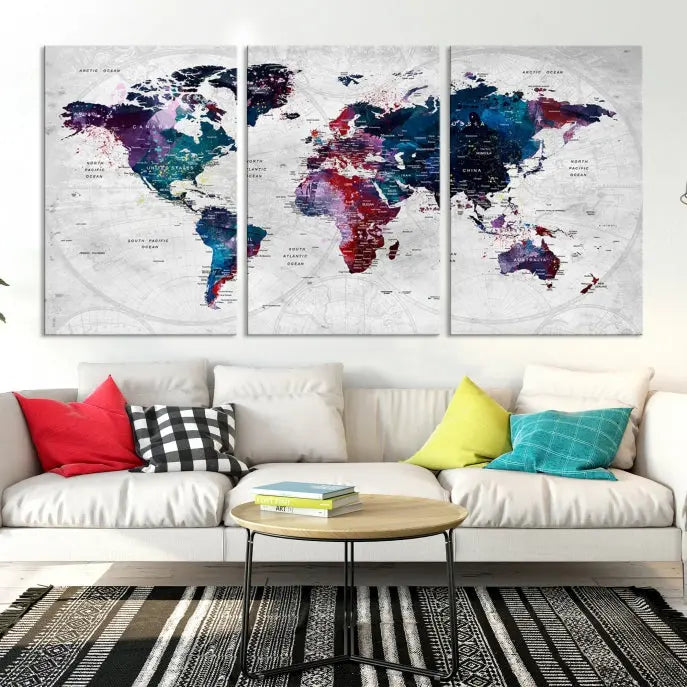 The "World Map Wall Art Watercolor Wall Art Canvas Print," a triptych featuring a vibrant world map, is gallery wrapped on museum-quality canvas and enhances the dark wall.