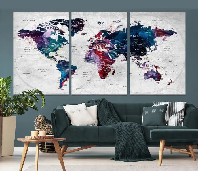 The "World Map Wall Art Watercolor Wall Art Canvas Print," a triptych featuring a vibrant world map, is gallery wrapped on museum-quality canvas and enhances the dark wall.