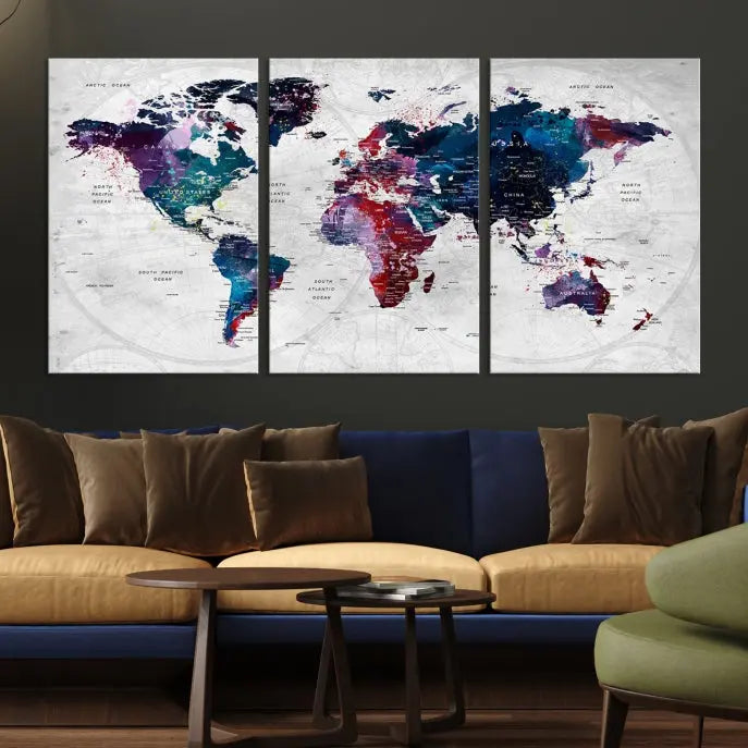 The "World Map Wall Art Watercolor Wall Art Canvas Print," a triptych featuring a vibrant world map, is gallery wrapped on museum-quality canvas and enhances the dark wall.