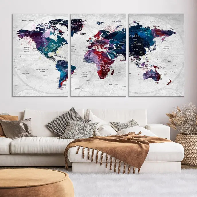 The "World Map Wall Art Watercolor Wall Art Canvas Print," a triptych featuring a vibrant world map, is gallery wrapped on museum-quality canvas and enhances the dark wall.