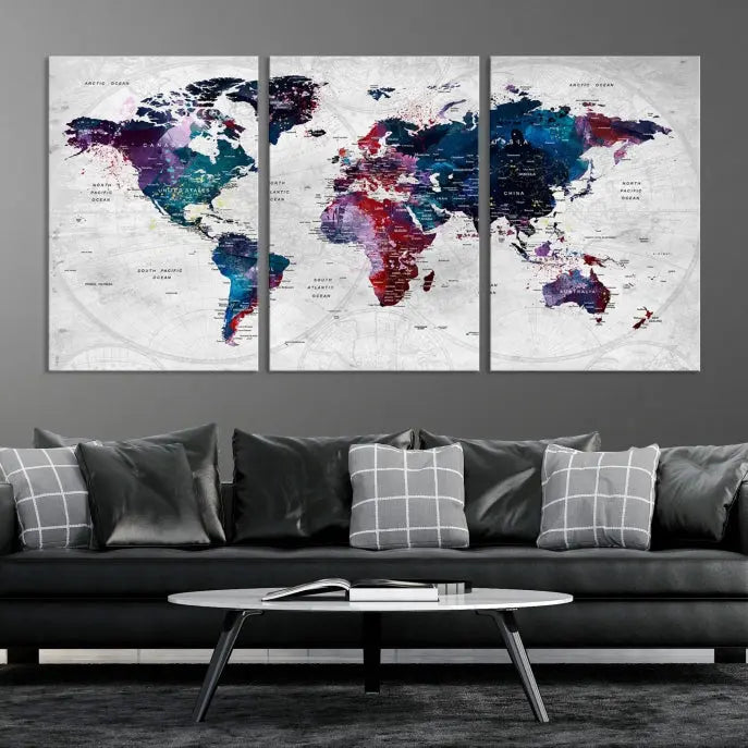 The "World Map Wall Art Watercolor Wall Art Canvas Print," a triptych featuring a vibrant world map, is gallery wrapped on museum-quality canvas and enhances the dark wall.