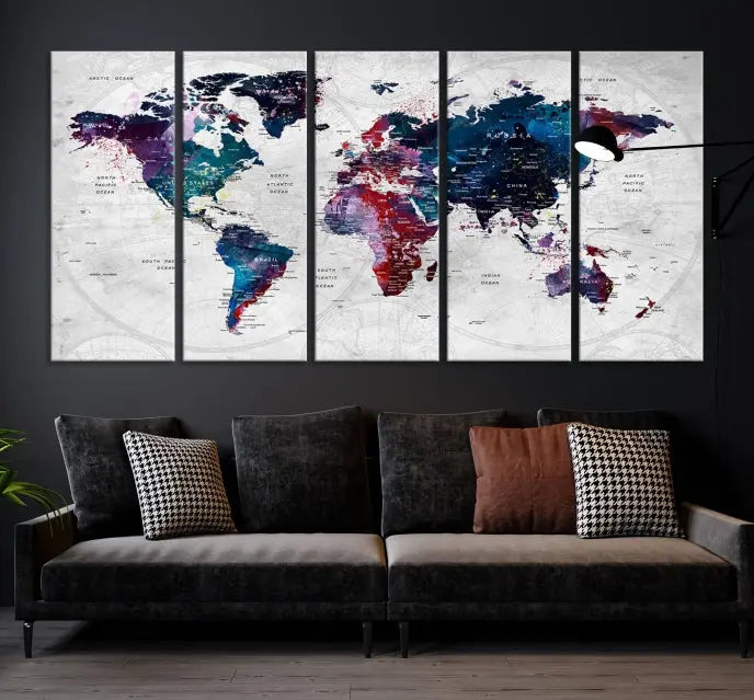 The "World Map Wall Art Watercolor Wall Art Canvas Print," a triptych featuring a vibrant world map, is gallery wrapped on museum-quality canvas and enhances the dark wall.