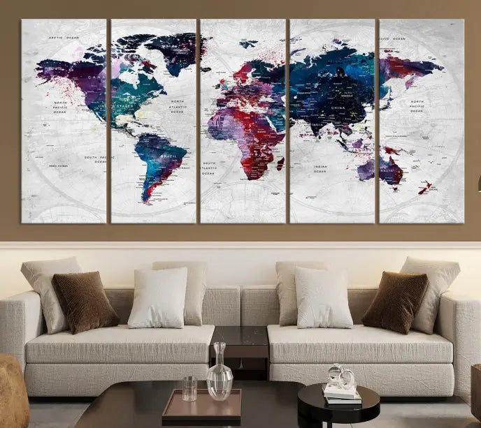 The "World Map Wall Art Watercolor Wall Art Canvas Print," a triptych featuring a vibrant world map, is gallery wrapped on museum-quality canvas and enhances the dark wall.