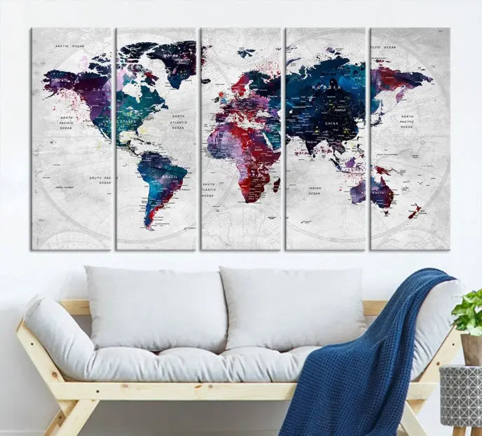 The "World Map Wall Art Watercolor Wall Art Canvas Print," a triptych featuring a vibrant world map, is gallery wrapped on museum-quality canvas and enhances the dark wall.