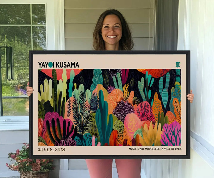 The vibrant canvas print of wall art features abstract plants, with the elegant text "Yayoi Kusama Wall Art Canvas Print" displayed on the colorful frame.