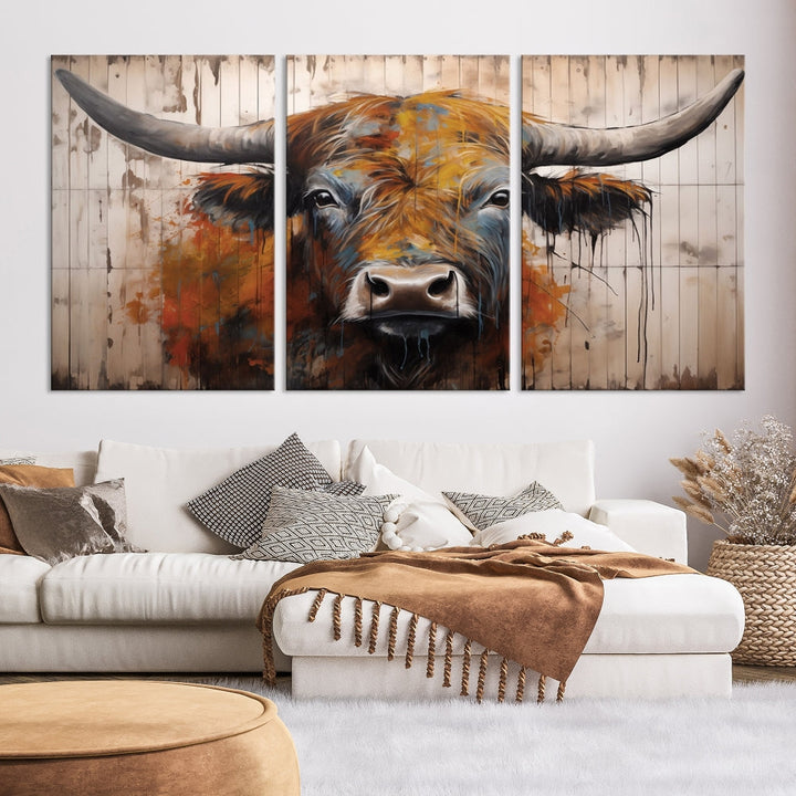 The "Abstract Bull Highland Cow Canvas Wall Art Print," displayed as a three-panel piece, adds vibrant rustic charm to a living room. Its depiction of a large, horned bull beautifully complements the elegance of modern farmhouse decor.