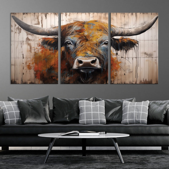 The "Abstract Bull Highland Cow Canvas Wall Art Print," displayed as a three-panel piece, adds vibrant rustic charm to a living room. Its depiction of a large, horned bull beautifully complements the elegance of modern farmhouse decor.