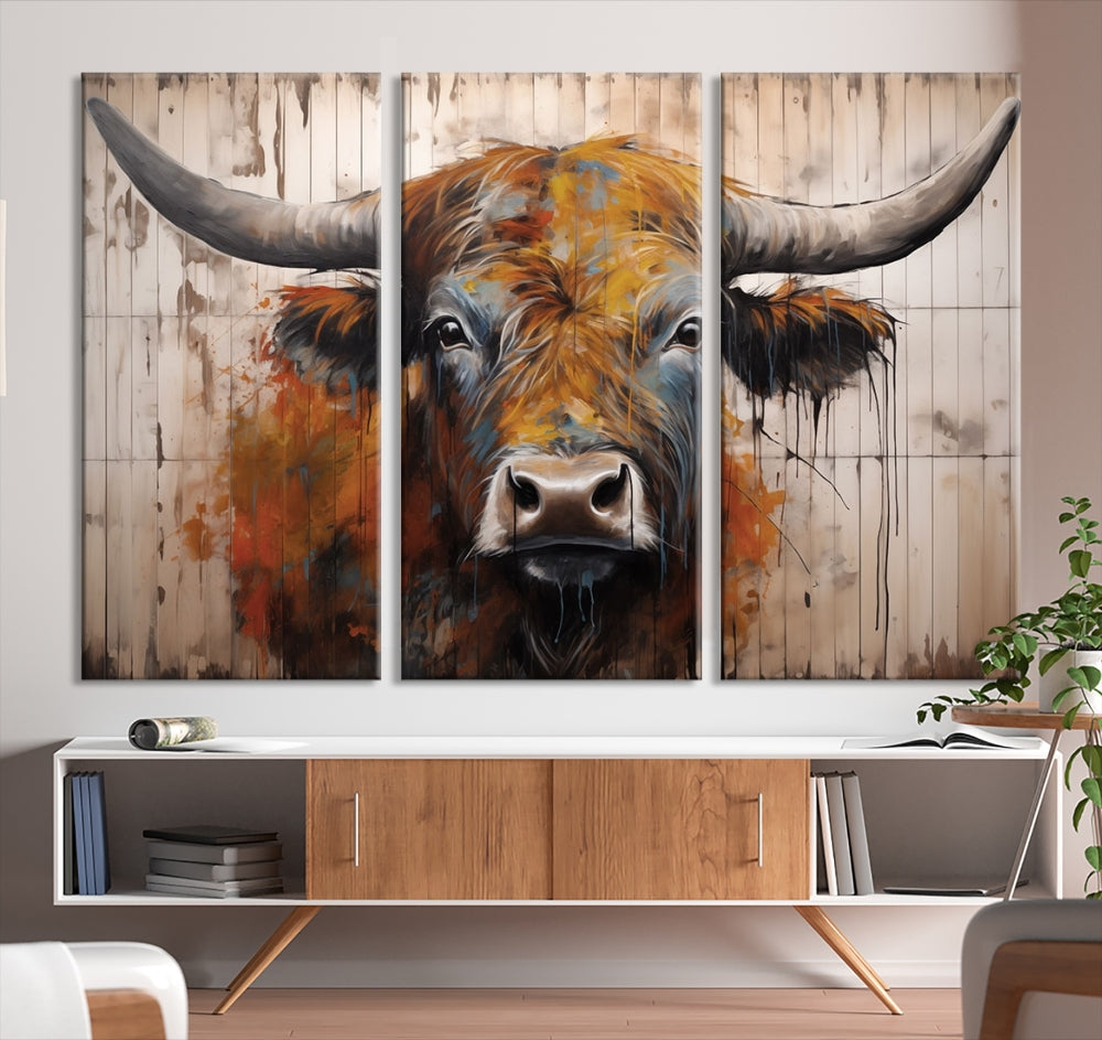 The "Abstract Bull Highland Cow Canvas Wall Art Print," displayed as a three-panel piece, adds vibrant rustic charm to a living room. Its depiction of a large, horned bull beautifully complements the elegance of modern farmhouse decor.