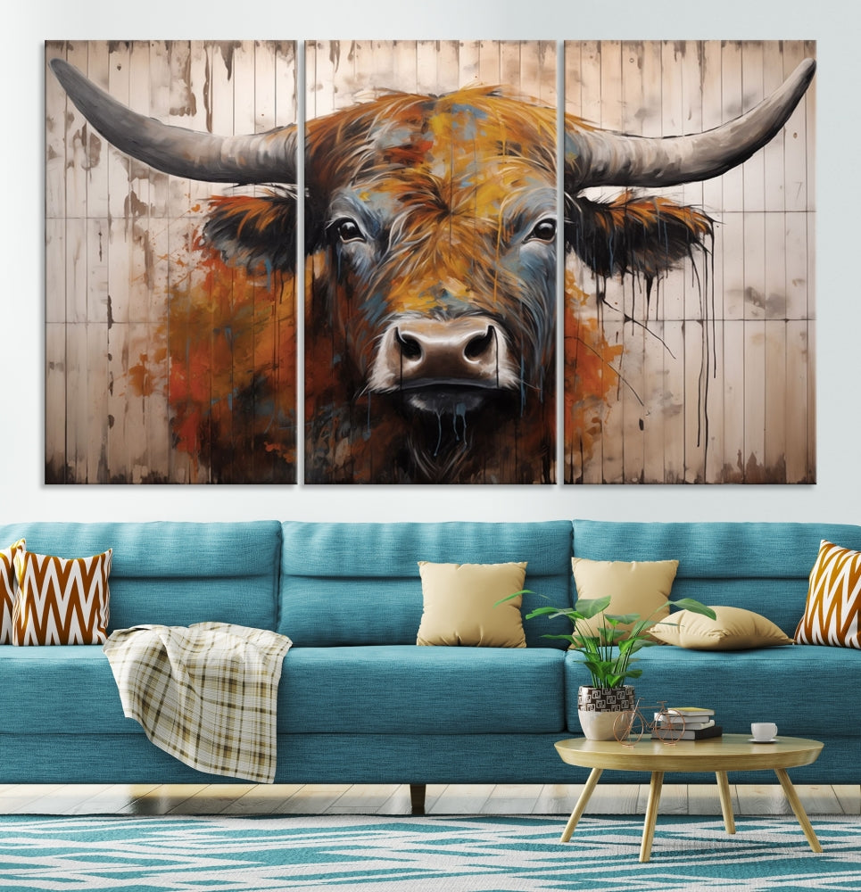 The "Abstract Bull Highland Cow Canvas Wall Art Print," displayed as a three-panel piece, adds vibrant rustic charm to a living room. Its depiction of a large, horned bull beautifully complements the elegance of modern farmhouse decor.