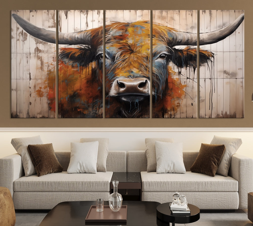 The "Abstract Bull Highland Cow Canvas Wall Art Print," displayed as a three-panel piece, adds vibrant rustic charm to a living room. Its depiction of a large, horned bull beautifully complements the elegance of modern farmhouse decor.