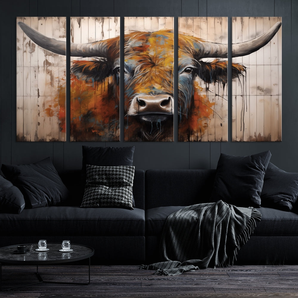 The "Abstract Bull Highland Cow Canvas Wall Art Print," displayed as a three-panel piece, adds vibrant rustic charm to a living room. Its depiction of a large, horned bull beautifully complements the elegance of modern farmhouse decor.