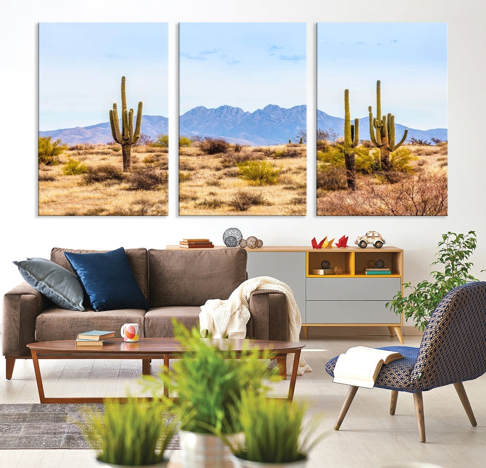 The Arizona Desert Cactus Wall Art Canvas Print, positioned above the console in a modern room, showcases a triptych desert landscape featuring cacti and mountains. Crafted on museum-quality polycotton canvas, it is finished with gallery-wrapped edges and an advanced UV-protective coating.