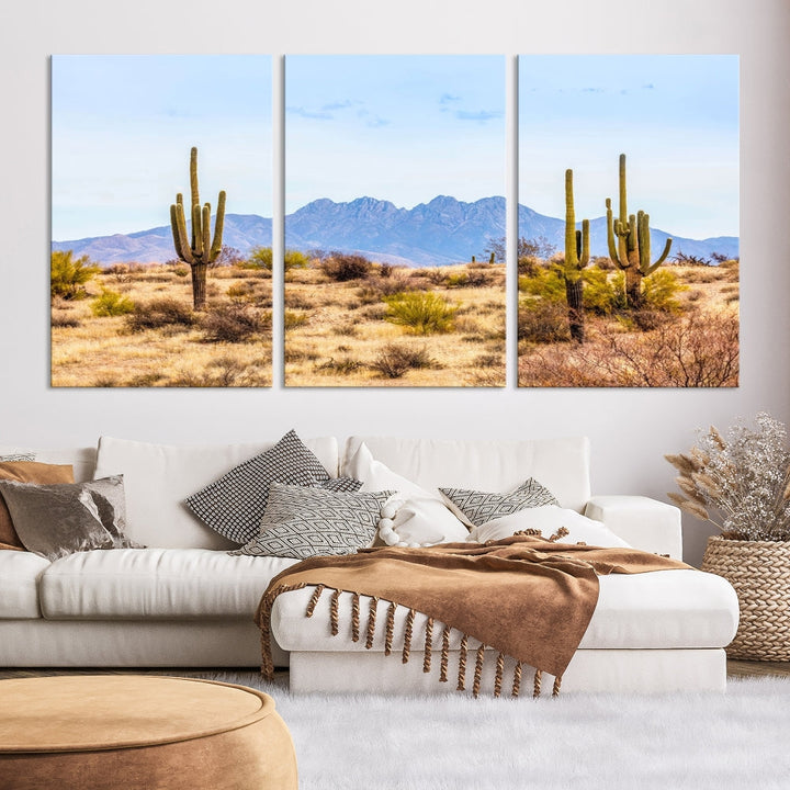 The Arizona Desert Cactus Wall Art Canvas Print, positioned above the console in a modern room, showcases a triptych desert landscape featuring cacti and mountains. Crafted on museum-quality polycotton canvas, it is finished with gallery-wrapped edges and an advanced UV-protective coating.