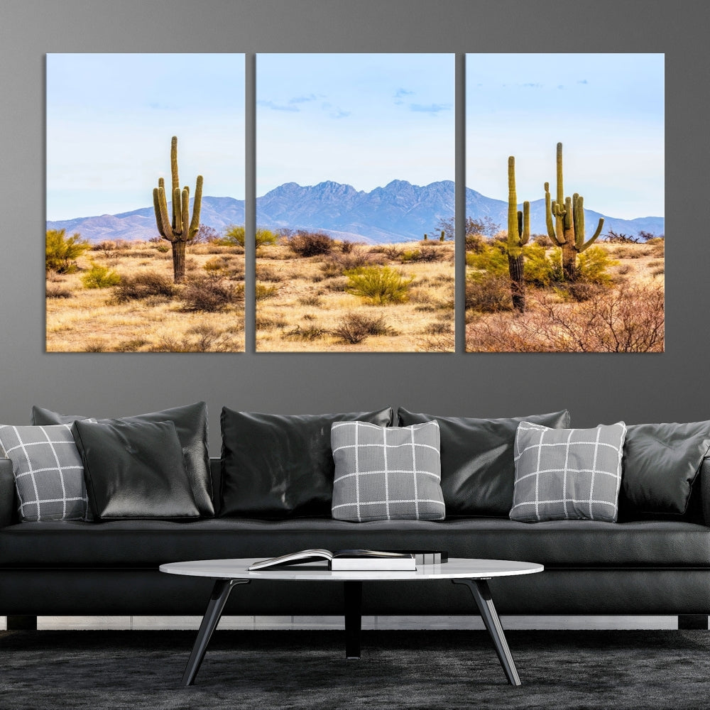 The Arizona Desert Cactus Wall Art Canvas Print, positioned above the console in a modern room, showcases a triptych desert landscape featuring cacti and mountains. Crafted on museum-quality polycotton canvas, it is finished with gallery-wrapped edges and an advanced UV-protective coating.