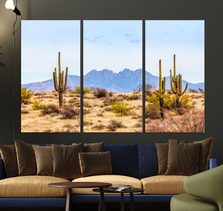 The Arizona Desert Cactus Wall Art Canvas Print, positioned above the console in a modern room, showcases a triptych desert landscape featuring cacti and mountains. Crafted on museum-quality polycotton canvas, it is finished with gallery-wrapped edges and an advanced UV-protective coating.