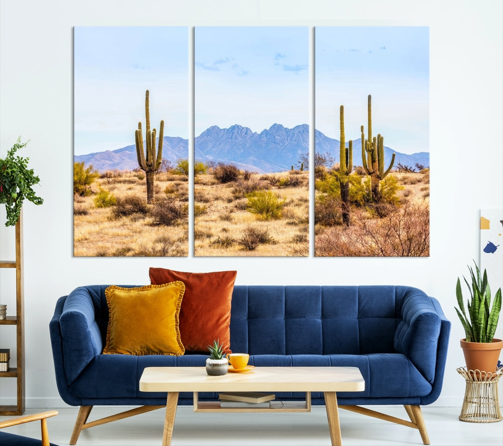 The Arizona Desert Cactus Wall Art Canvas Print, positioned above the console in a modern room, showcases a triptych desert landscape featuring cacti and mountains. Crafted on museum-quality polycotton canvas, it is finished with gallery-wrapped edges and an advanced UV-protective coating.