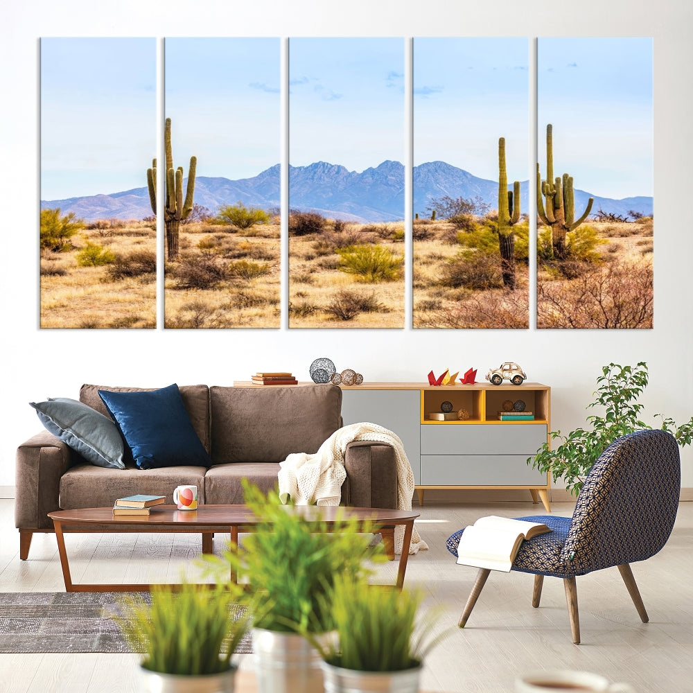 The Arizona Desert Cactus Wall Art Canvas Print, positioned above the console in a modern room, showcases a triptych desert landscape featuring cacti and mountains. Crafted on museum-quality polycotton canvas, it is finished with gallery-wrapped edges and an advanced UV-protective coating.