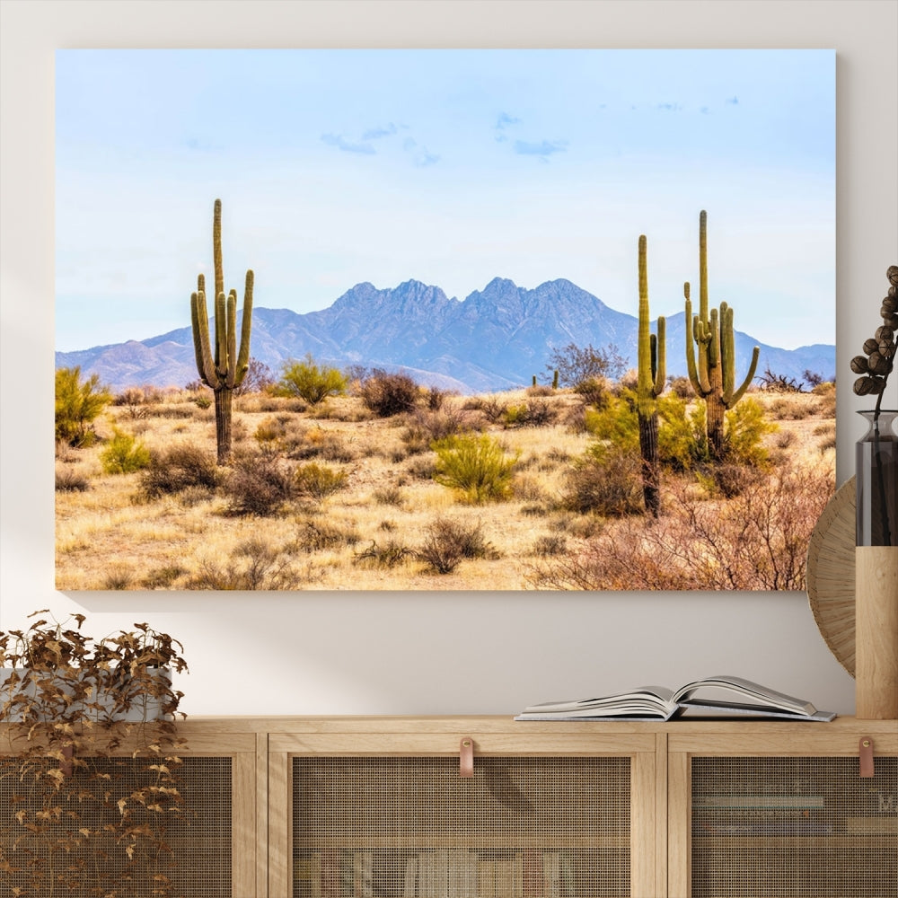 The Arizona Desert Cactus Wall Art Canvas Print, positioned above the console in a modern room, showcases a triptych desert landscape featuring cacti and mountains. Crafted on museum-quality polycotton canvas, it is finished with gallery-wrapped edges and an advanced UV-protective coating.