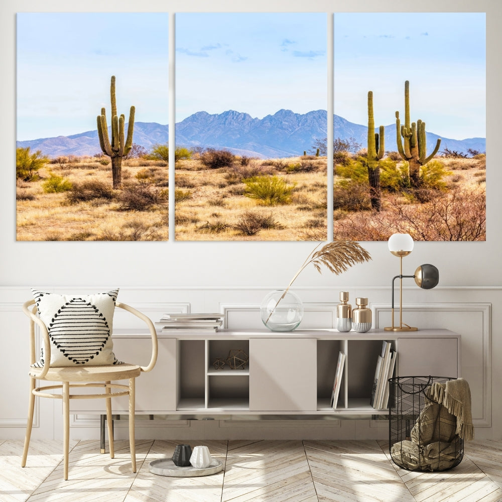 The Arizona Desert Cactus Wall Art Canvas Print, positioned above the console in a modern room, showcases a triptych desert landscape featuring cacti and mountains. Crafted on museum-quality polycotton canvas, it is finished with gallery-wrapped edges and an advanced UV-protective coating.