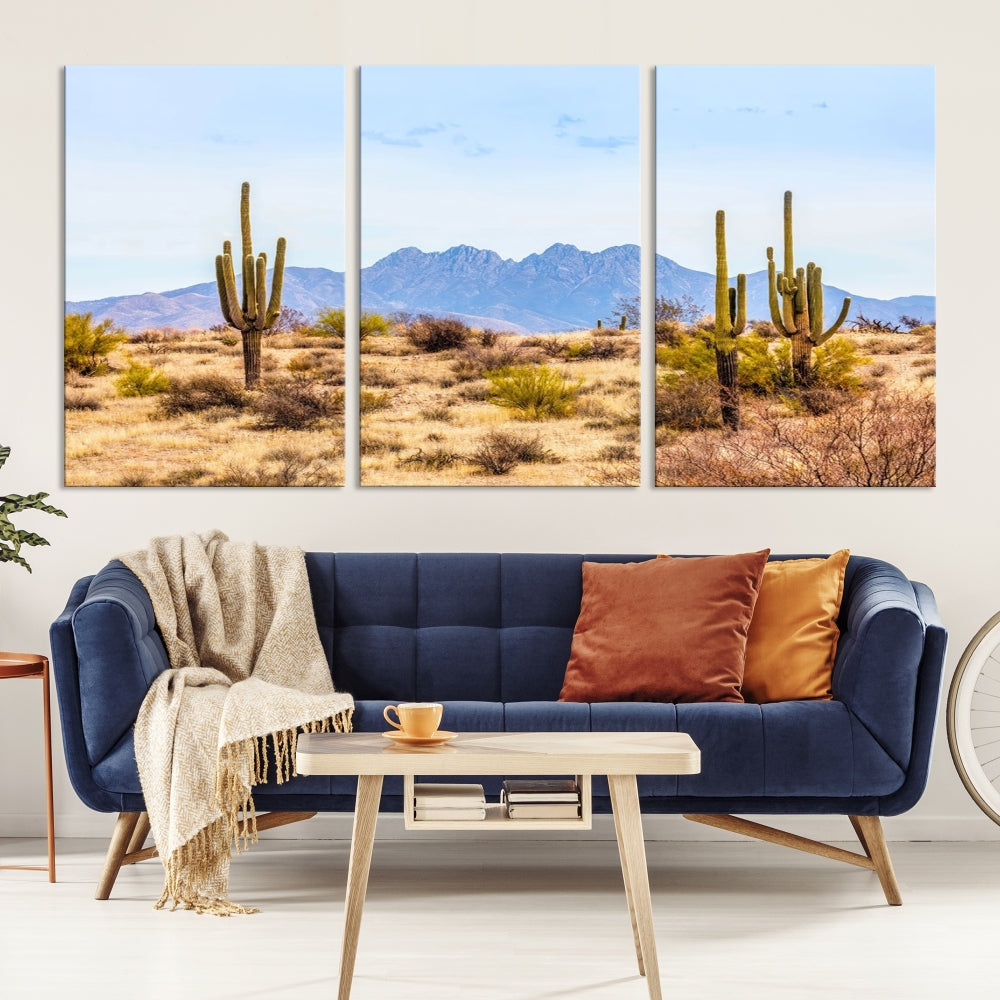 The Arizona Desert Cactus Wall Art Canvas Print, positioned above the console in a modern room, showcases a triptych desert landscape featuring cacti and mountains. Crafted on museum-quality polycotton canvas, it is finished with gallery-wrapped edges and an advanced UV-protective coating.