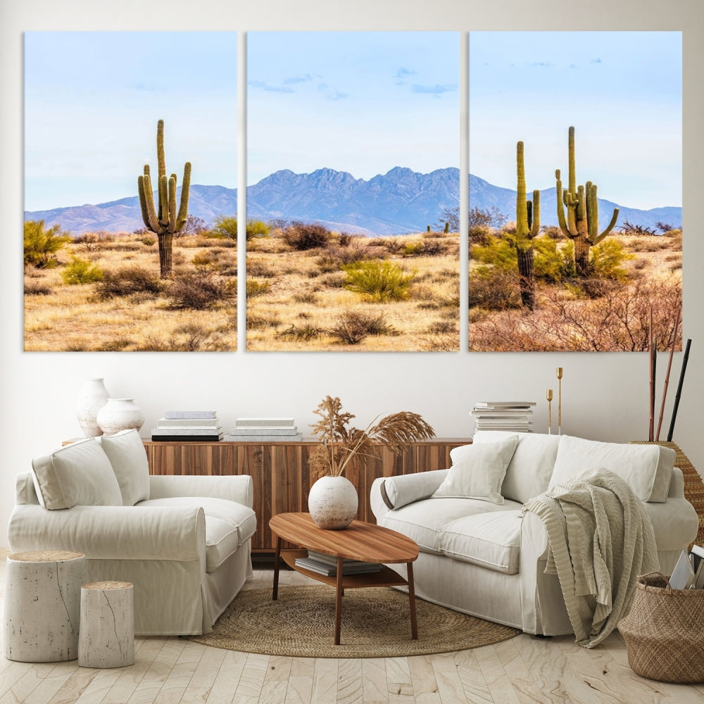 The Arizona Desert Cactus Wall Art Canvas Print, positioned above the console in a modern room, showcases a triptych desert landscape featuring cacti and mountains. Crafted on museum-quality polycotton canvas, it is finished with gallery-wrapped edges and an advanced UV-protective coating.