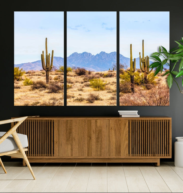 The Arizona Desert Cactus Wall Art Canvas Print, positioned above the console in a modern room, showcases a triptych desert landscape featuring cacti and mountains. Crafted on museum-quality polycotton canvas, it is finished with gallery-wrapped edges and an advanced UV-protective coating.