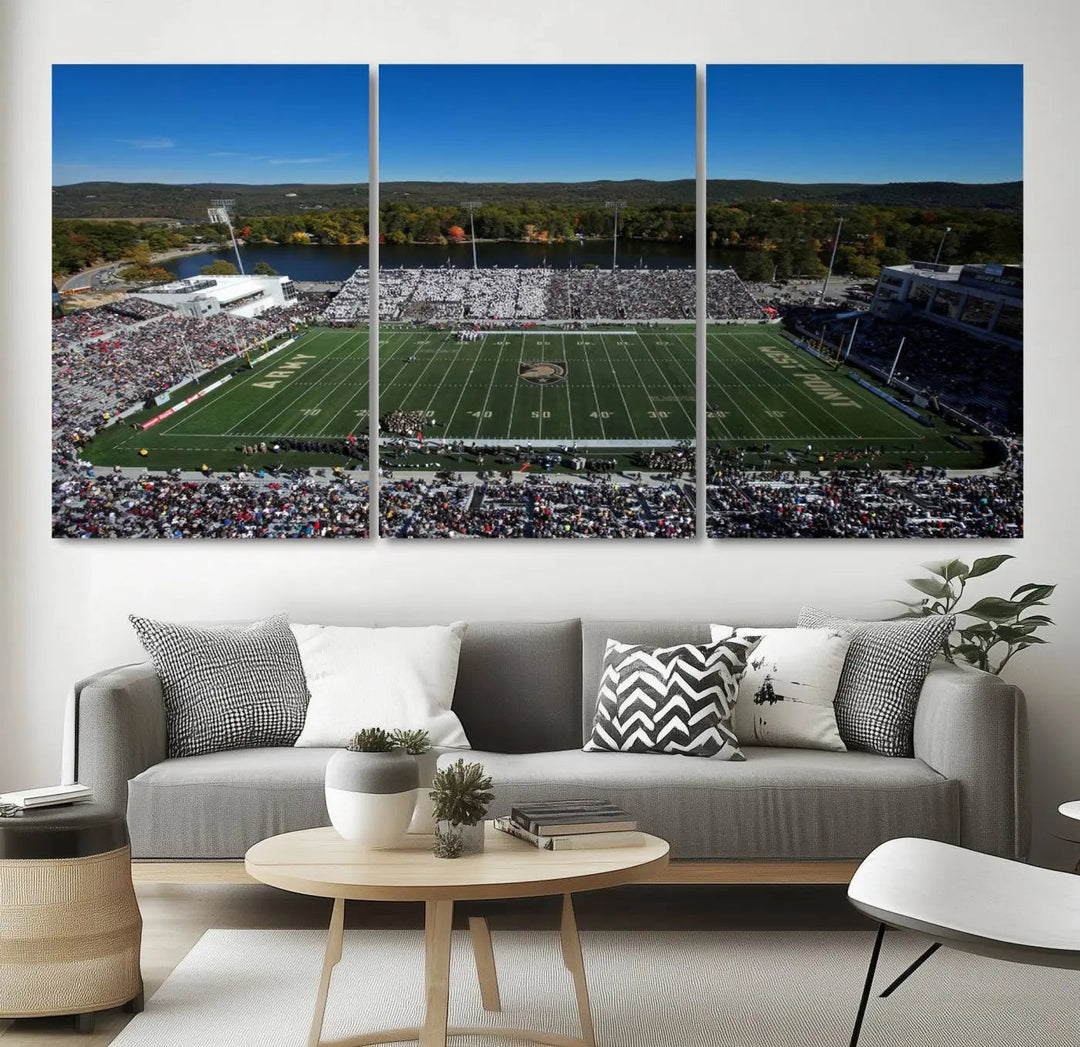 The Army Black Knights Football Team Print on West Point Michie Stadium is showcased with an aerial view capturing a lively football stadium surrounded by lush trees and a river. This wall art is printed on museum-quality canvas and mounted on a stretched wood frame.