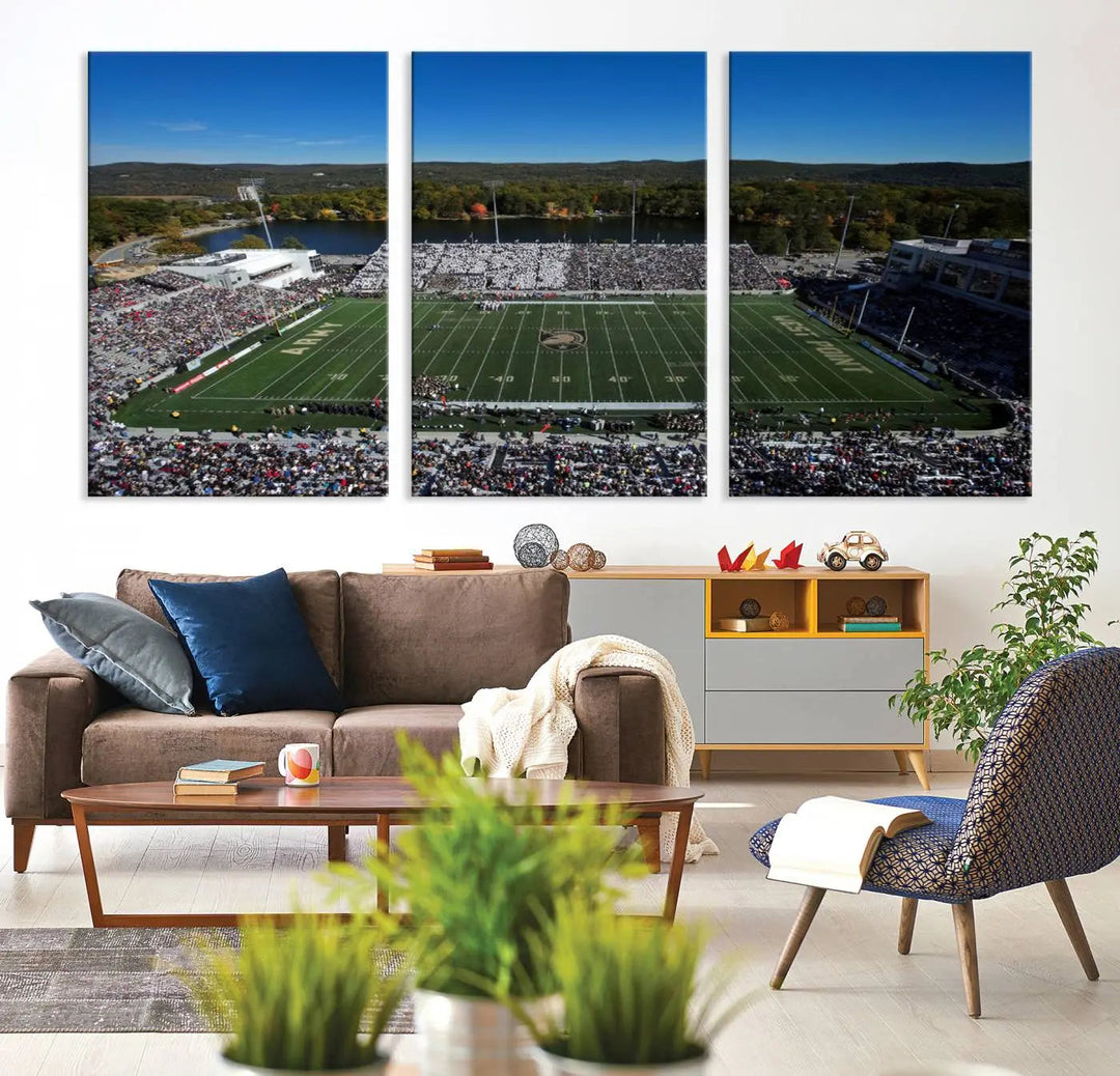 The Army Black Knights Football Team Print on West Point Michie Stadium is showcased with an aerial view capturing a lively football stadium surrounded by lush trees and a river. This wall art is printed on museum-quality canvas and mounted on a stretched wood frame.