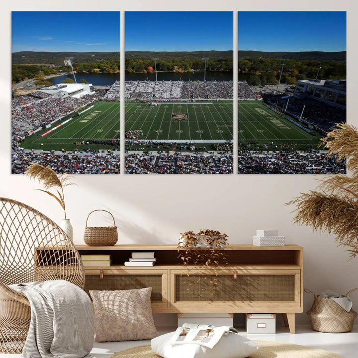 The Army Black Knights Football Team Print on West Point Michie Stadium is showcased with an aerial view capturing a lively football stadium surrounded by lush trees and a river. This wall art is printed on museum-quality canvas and mounted on a stretched wood frame.