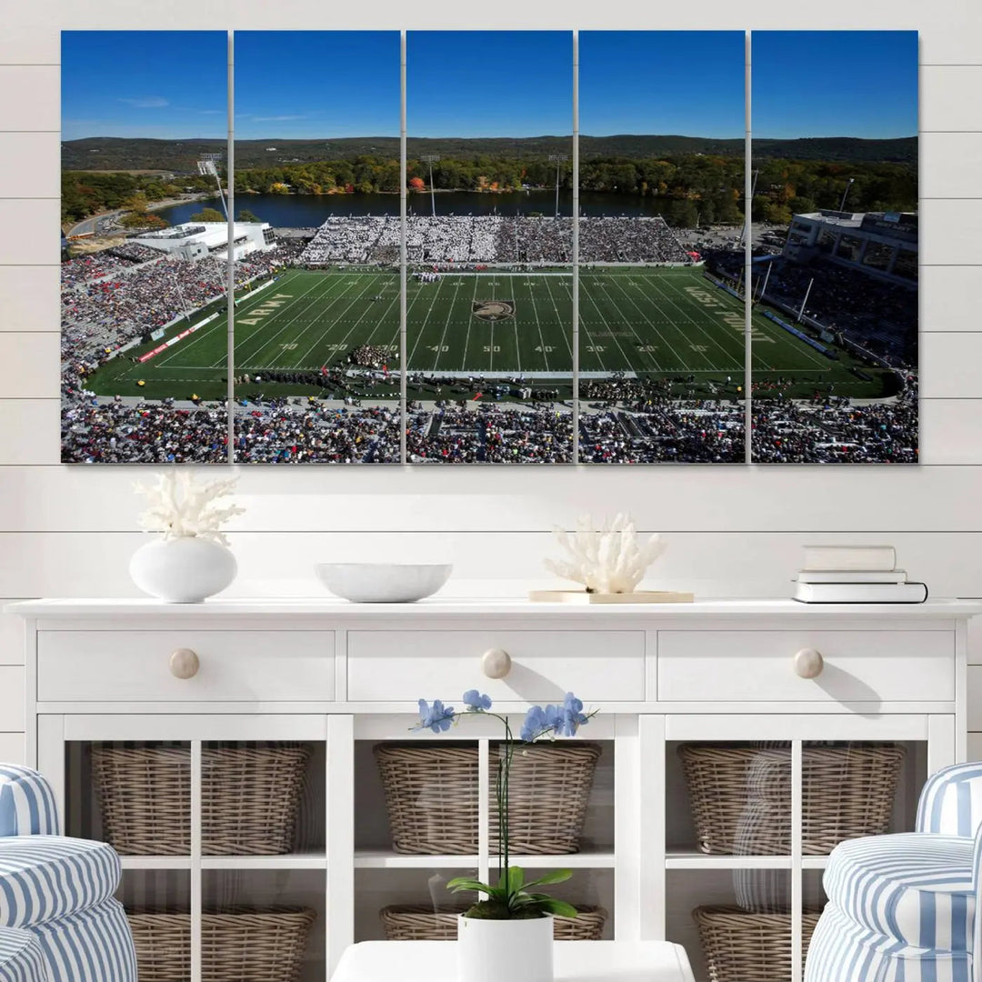 The Army Black Knights Football Team Print on West Point Michie Stadium is showcased with an aerial view capturing a lively football stadium surrounded by lush trees and a river. This wall art is printed on museum-quality canvas and mounted on a stretched wood frame.