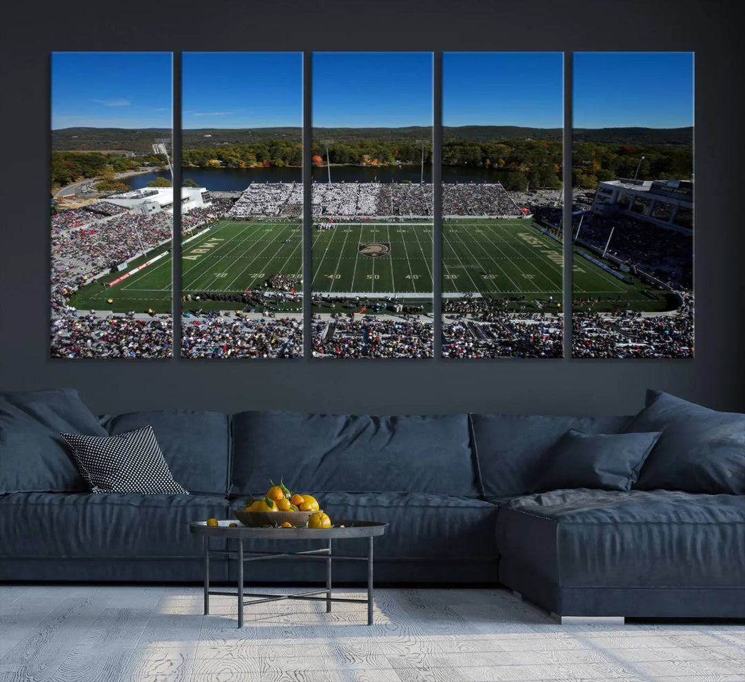 The Army Black Knights Football Team Print on West Point Michie Stadium is showcased with an aerial view capturing a lively football stadium surrounded by lush trees and a river. This wall art is printed on museum-quality canvas and mounted on a stretched wood frame.