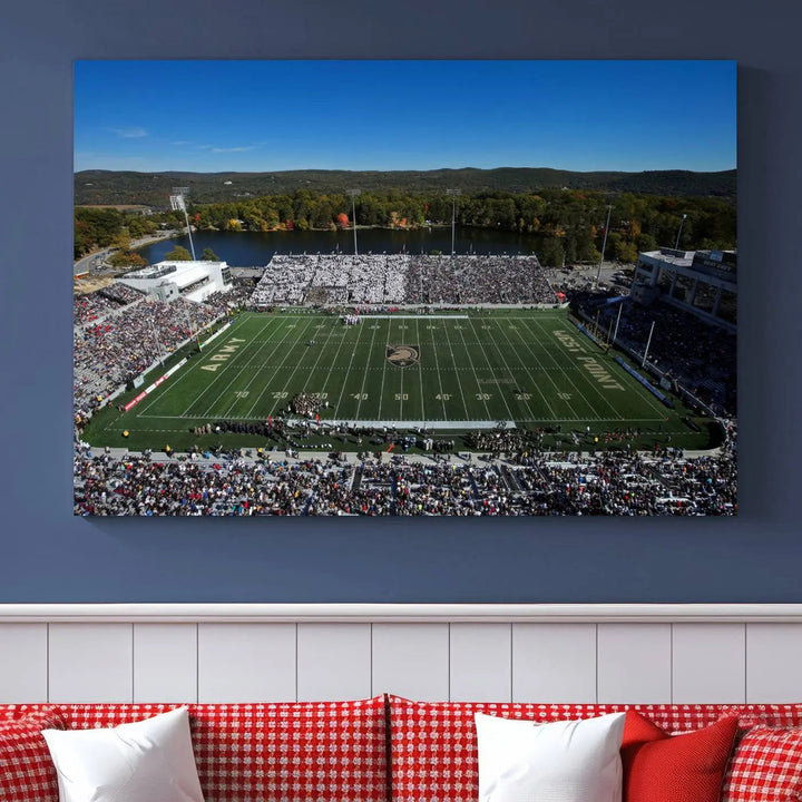 The Army Black Knights Football Team Print on West Point Michie Stadium is showcased with an aerial view capturing a lively football stadium surrounded by lush trees and a river. This wall art is printed on museum-quality canvas and mounted on a stretched wood frame.