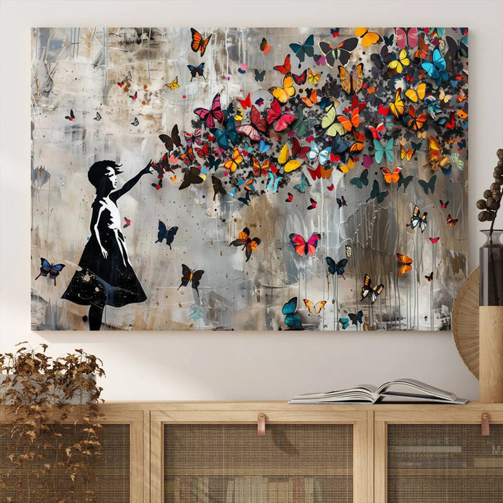 The Banksy Butterfly Girl 3-piece canvas art showcases a silhouette of a girl surrounded by colorful butterflies, perfect for modern living room decor.