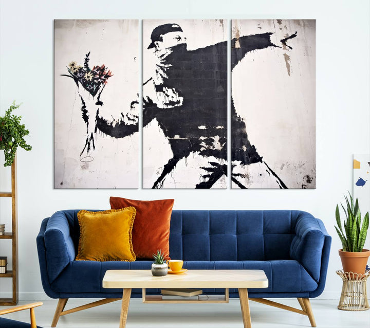 The living room features a split-panel art piece named "Banksy Flower Throw Graffiti Street Wall Art Canvas Print," gallery wrapped on museum-quality polycotton canvas and accentuated by modern decor elements.